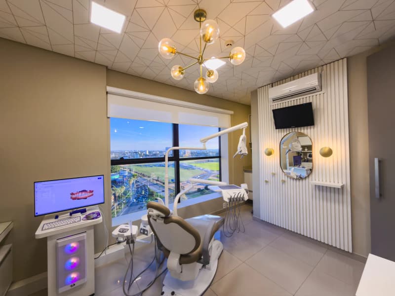 Consultório com cadeira odontológica e janela ampla para a cidade