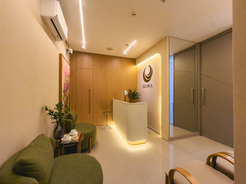 Recepção da Elora Odontologia Integrada, com poltronas verdes e iluminação indireta